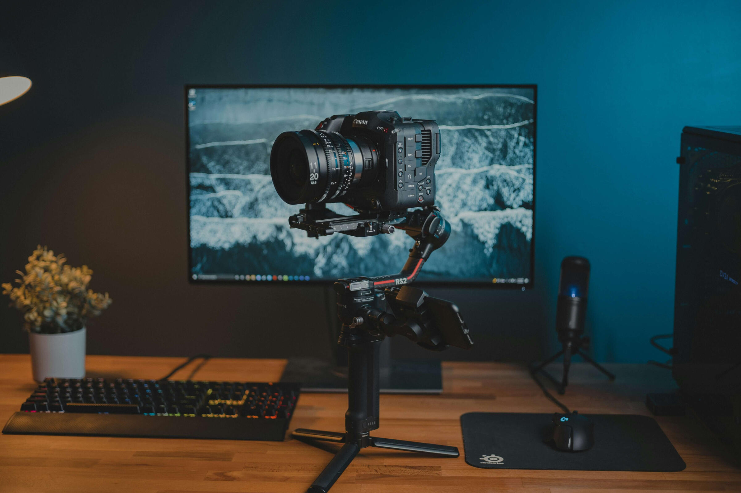 Bistrón content creation service Canon EOS cinema camera on a gimbal stabilizer in a tech setup with a monitor and keyboard.